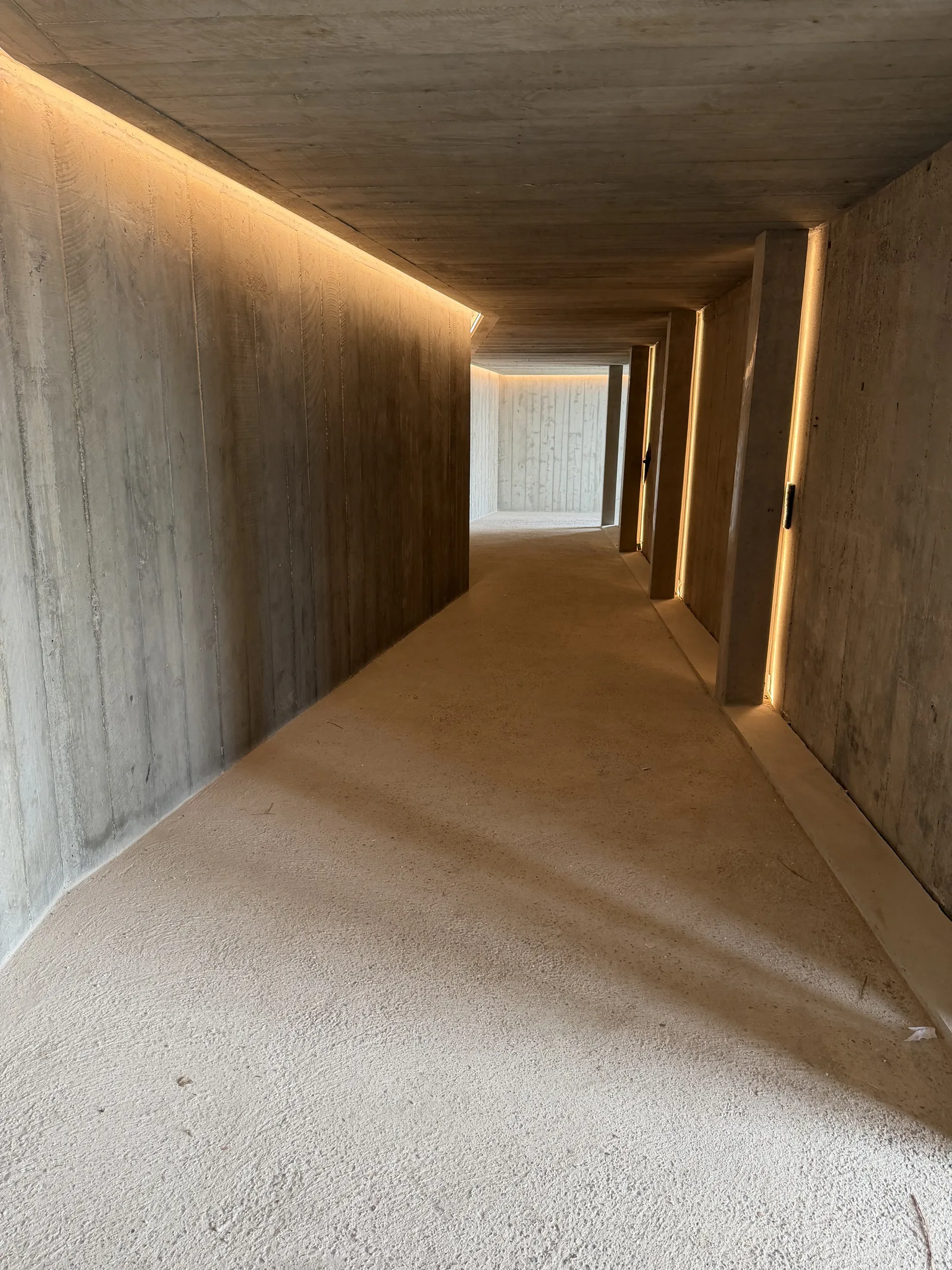 Couloir technique en béton brut souligné d'un éclairage LED continu — villa domotique Crestron au Pyla-sur-Mer, Bassin d'Arcachon (ADEPP Control)